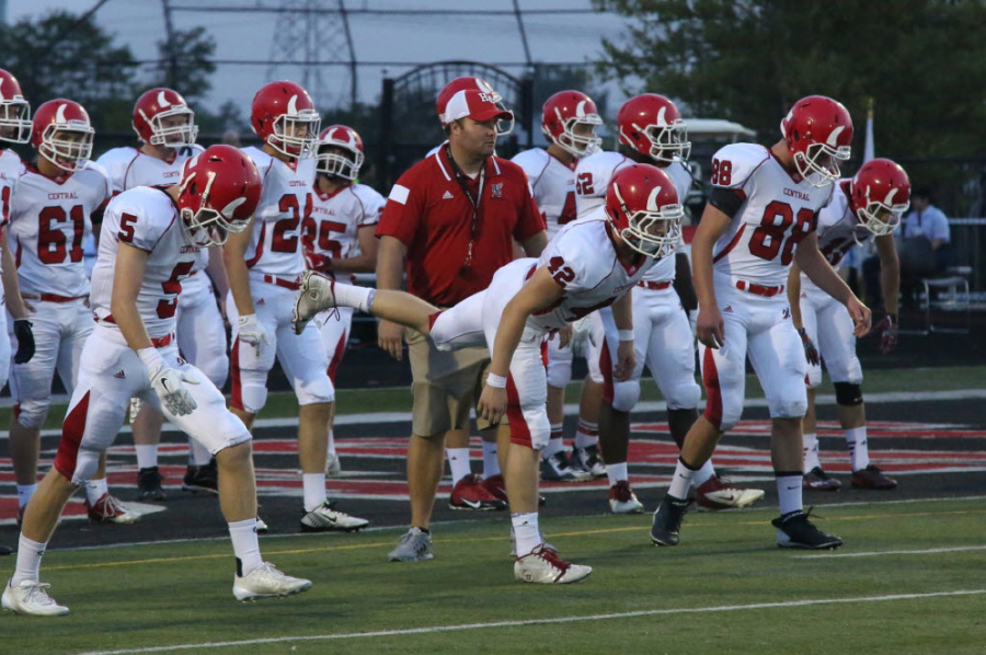 Hartman+%28red+polo%29+warms+up+with+the+varsity+football+players+before+a+game.