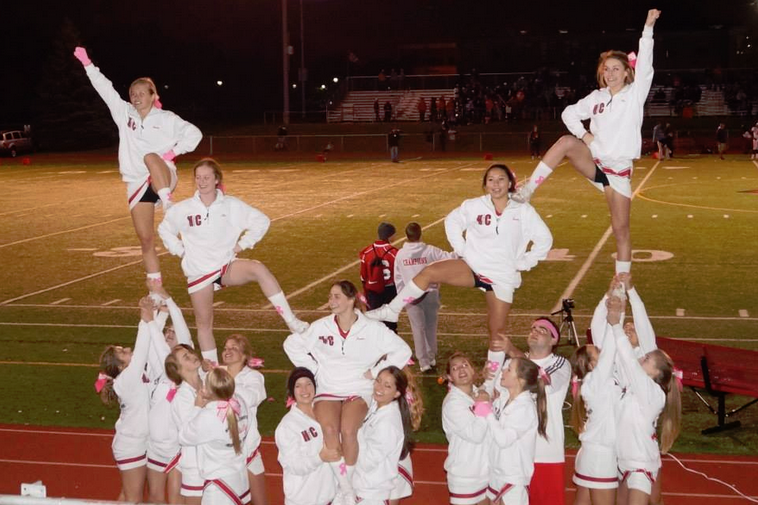 The varsity cheerleading squad executes a formation at the pink out football game against Oak Park.
