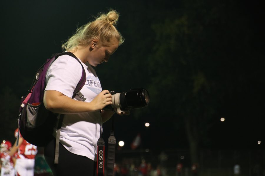 Paige Wilder, junior, closely looks at her shots at a football game. 