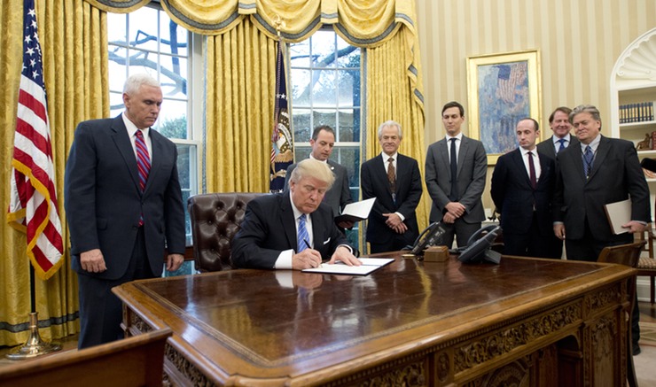 Trump signs an executive order in front of Vice President Mike Pence and other cabinet members. 