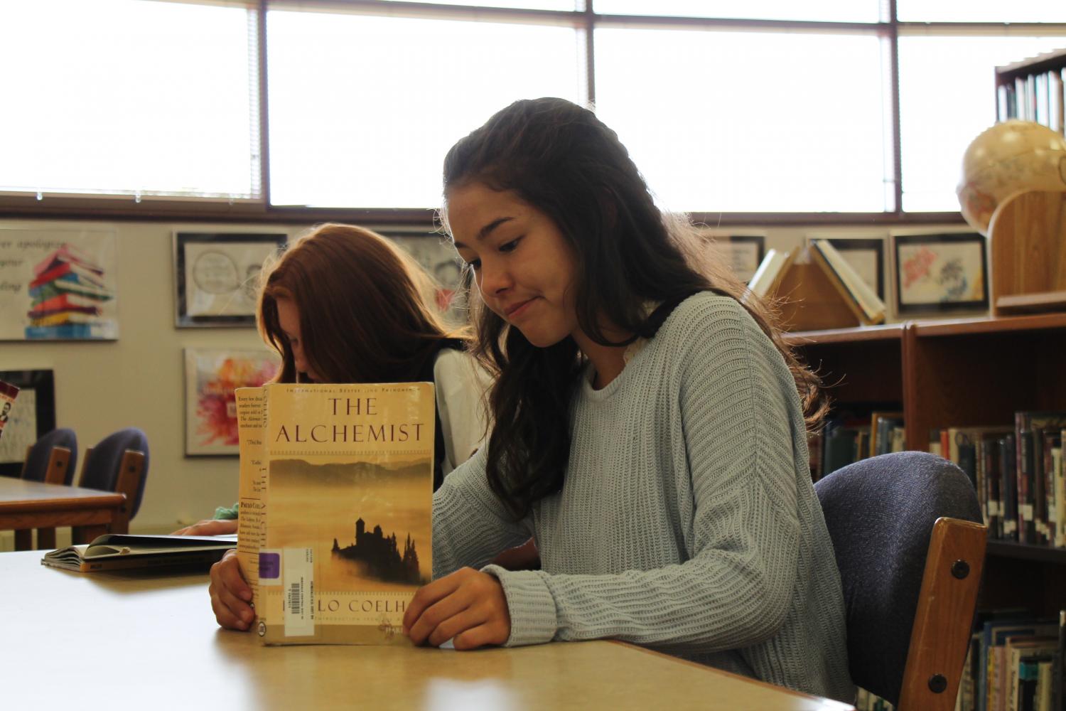 Freshman Rei Hemmer sits in the library reading her summer reading book during her English class. 