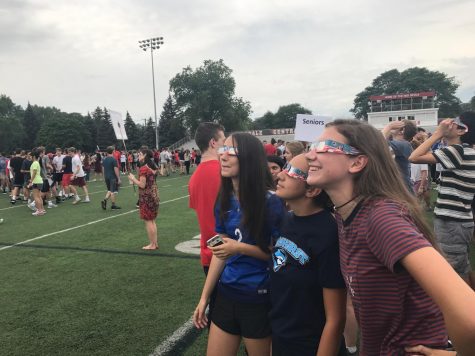 Seniors Elaine Carter, Jacinda Eskander, and Kerri Kenney watch the solar eclipse on the football field.