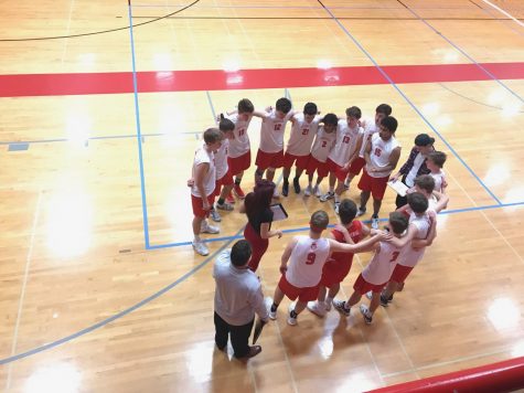 The boys varsity volleyball team gathers together at practice to discuss their plan for the upcoming game.