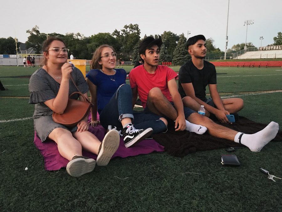 A couple of students sat on  Dickinson field to view Spider Homecoming.