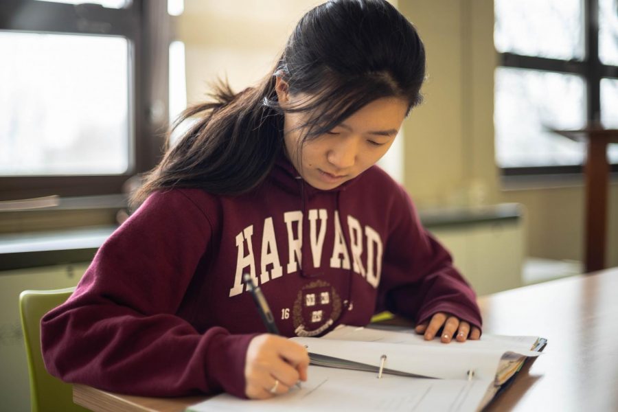 Melissa Li, senior, does homework while wearing a Harvard hoodie. Li aspired to attend an elite school since freshman year.