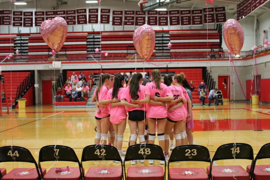 The sophomore team huddles in between sets, in front of balloons setup that decorated the event.