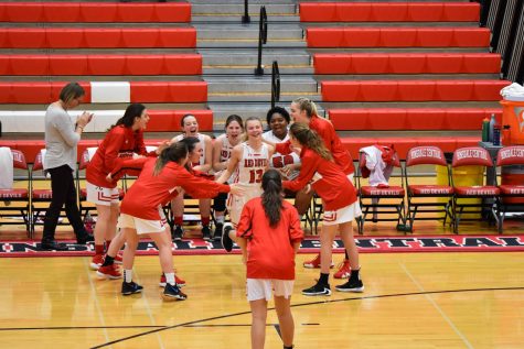 The basketball players cheer for each other before the game begins. 