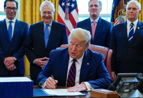 President Donald Trump, surrounded by key legislators, ratifies a $2 trillion stimulus package on March 27. 