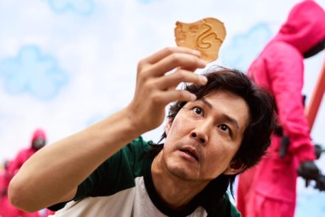 Seong Gi-hun, or player 456, holds up a dalgona candy as part of the Honeycomb Challenge.