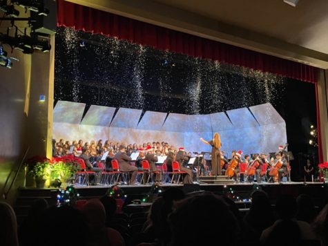 The choirs and orchestra perform an arrangement of Jingle Bells as fake snow falls around them. 
