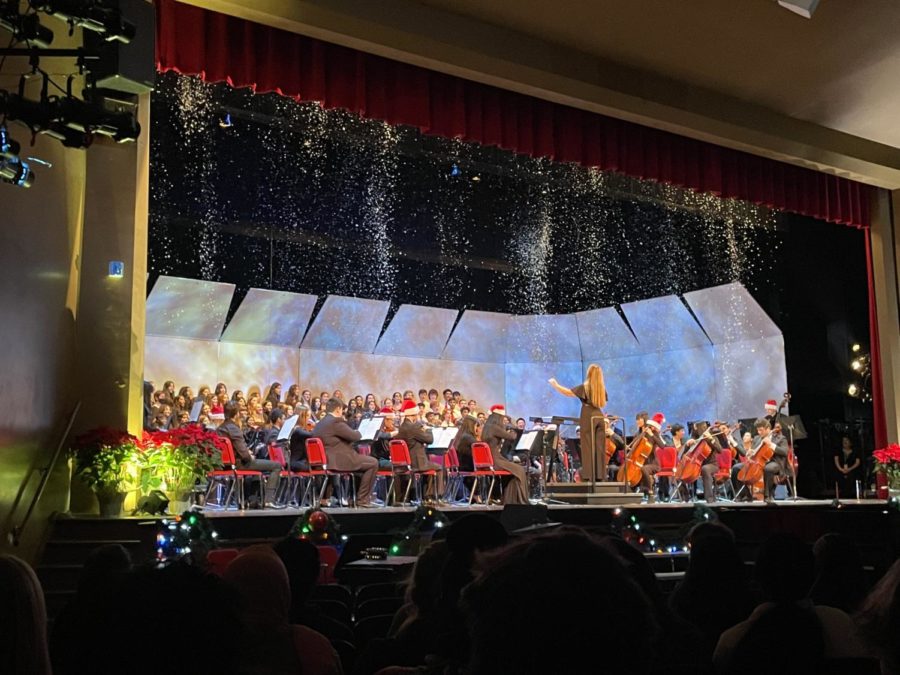 The choirs and orchestra perform an arrangement of Jingle Bells as fake snow falls around them. 